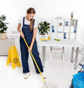 smiling young cleaner washing floor with mop